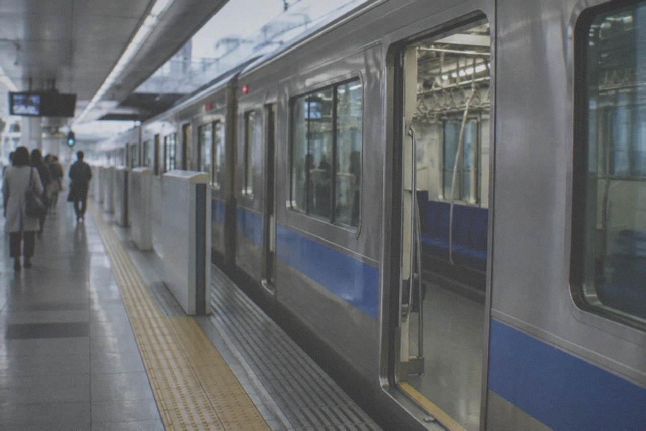 A subway platform at Fukuoka Airport station with a train waiting at the doors