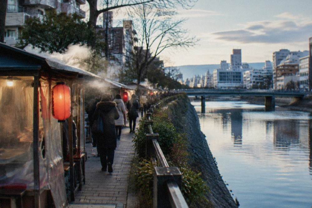 Steam rising from food stalls along a river at night in winter