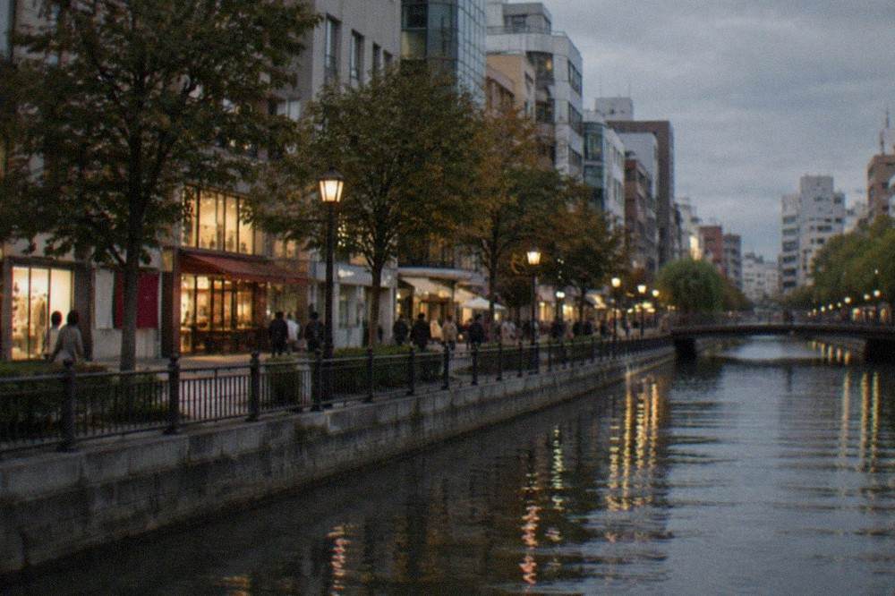 Evening view of a canal-side shopping street with illuminated storefronts in central Fukuoka
