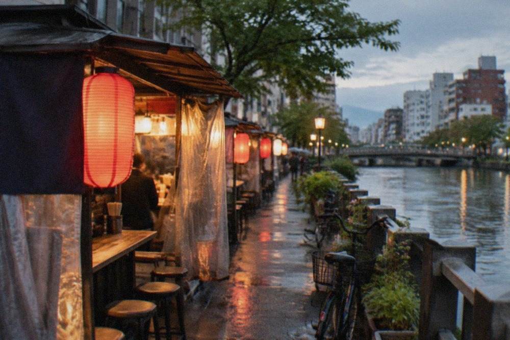Canal-side street food stalls glowing under lanterns beside a river in Fukuoka at night