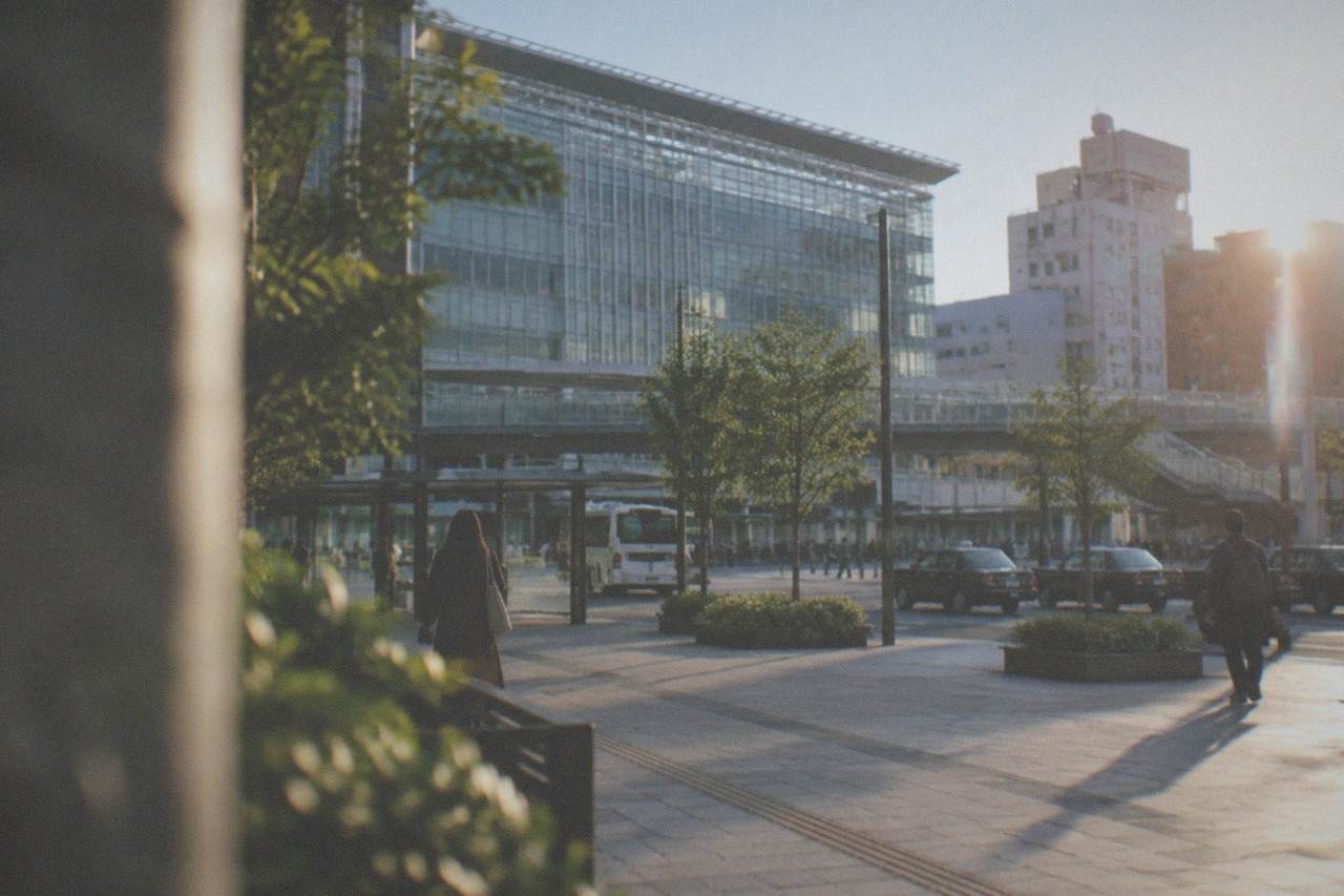 Hakata Station's modern glass facade above the surrounding city blocks under a clear sky