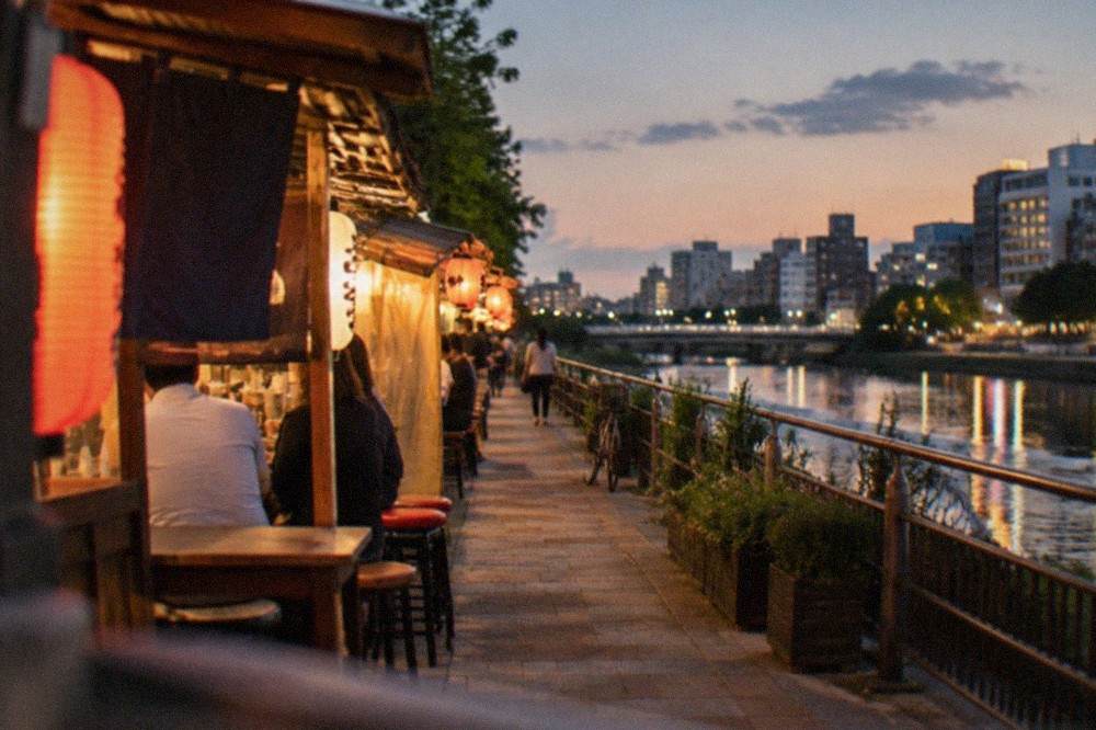 Evening view of illuminated food stalls along a river in Fukuoka
