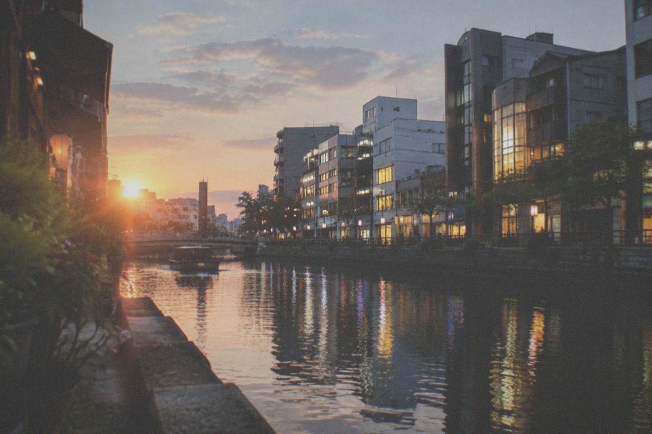 Canal running between illuminated buildings in the Hakata ward of Fukuoka at dusk