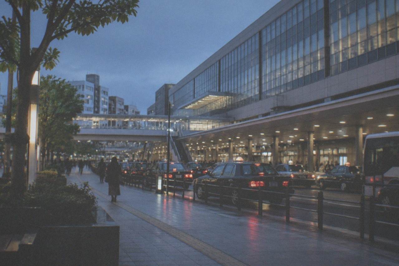 The Hakata Station building exterior with a departures board and taxi rank