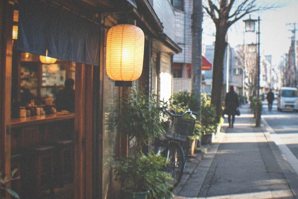 A warm restaurant interior with lantern light glowing over wooden counter seating