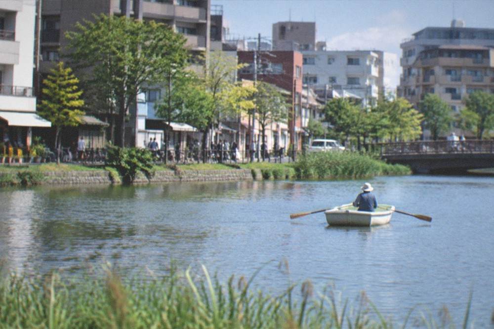 A rowboat drifting on a wide lake with reeds along the near shore