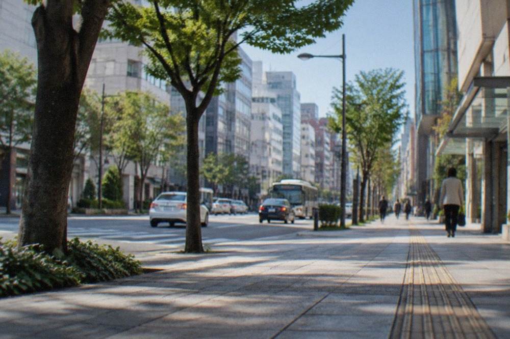 A wide avenue in Tenjin lined with department stores and glass office towers under a clear sky