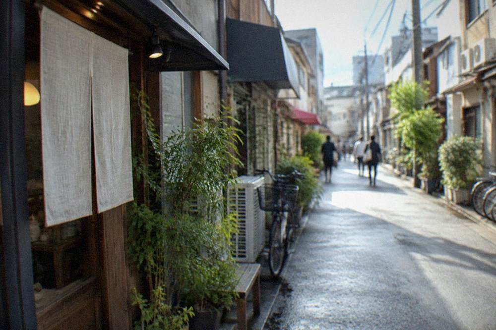 A narrow lane in Daimyo with small boutique storefronts and hanging signs