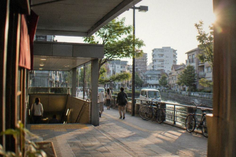 A subway station entrance on a sunny street with signs above the stairwell