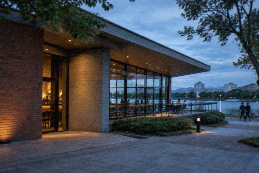 Museum cafe terrace with tables overlooking a park pond through large windows