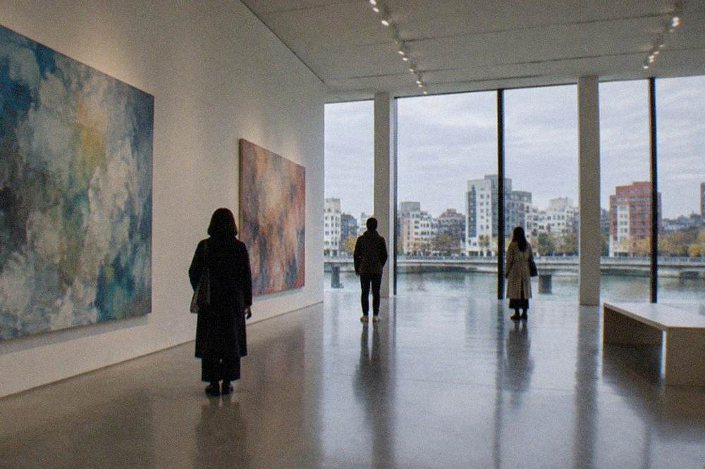 Visitors viewing large contemporary paintings hung in a bright gallery hall