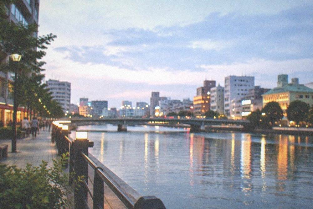 Naka riverside promenade with illuminated buildings reflected in the water at dusk