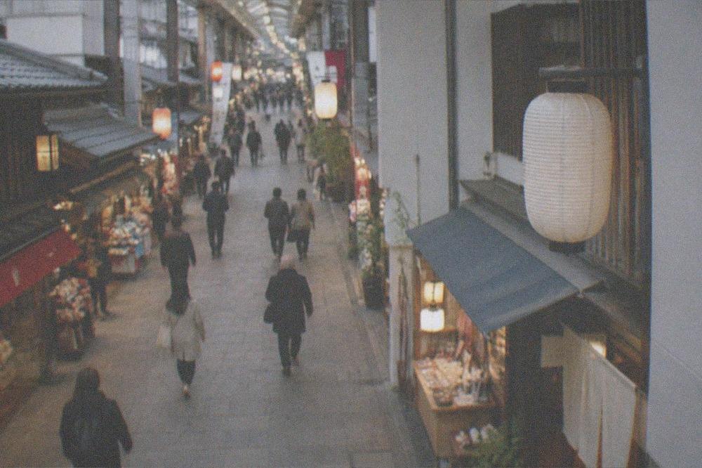 Lantern-lit shopping arcade with small shops and signage under a glass roof