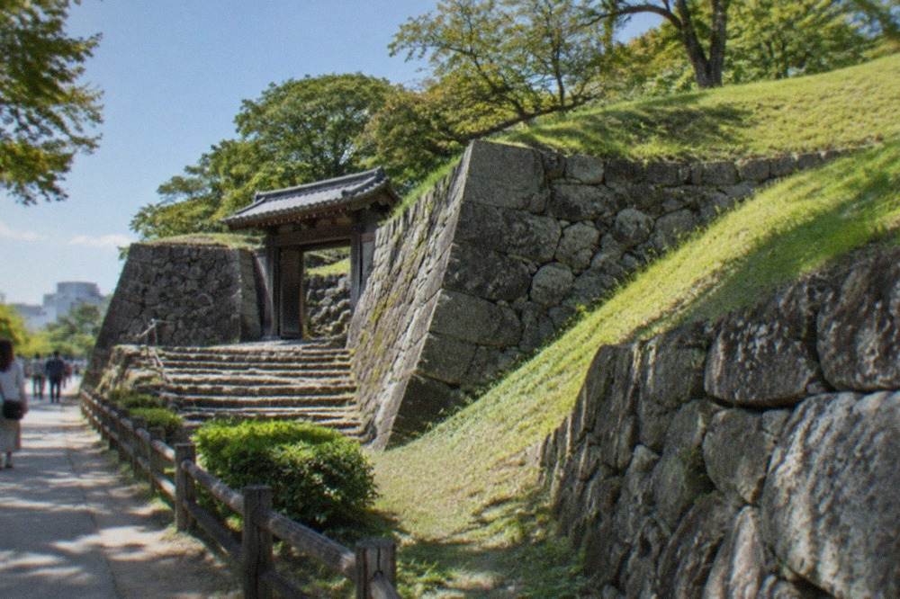 Grassy castle ruins embankment with stone walls under a blue sky