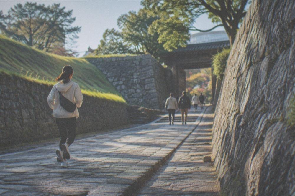 Visitors walking a stone ramp path between castle walls in morning light