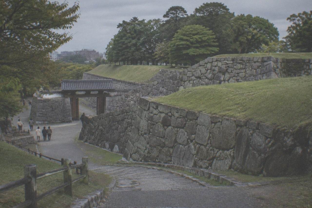 Stone castle wall with green park trees behind it