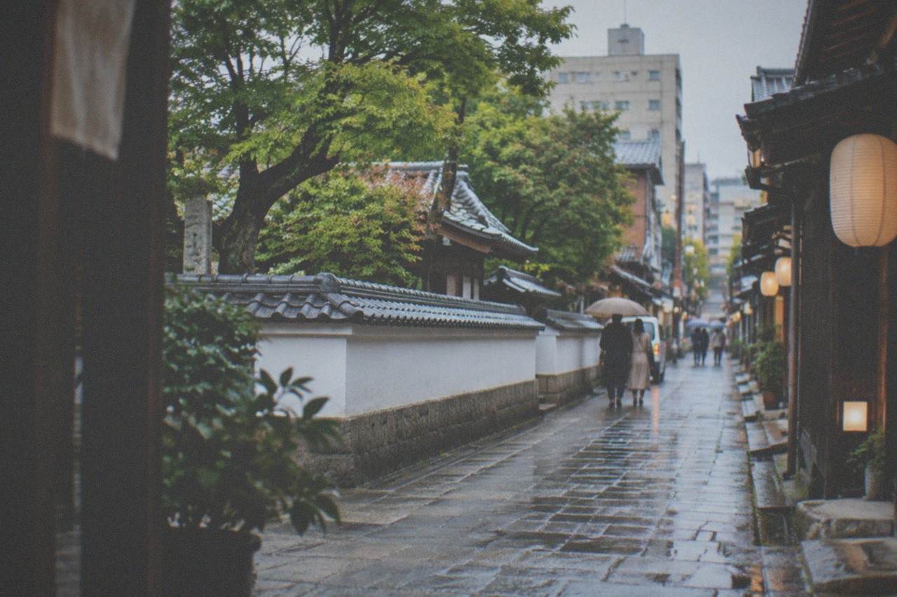 A narrow historic street in Hakata Old Town with traditional wooden building facades and lanterns in the late afternoon.