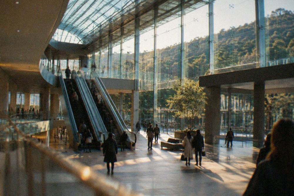 Interior atrium of a museum with tall glass roof and long escalators