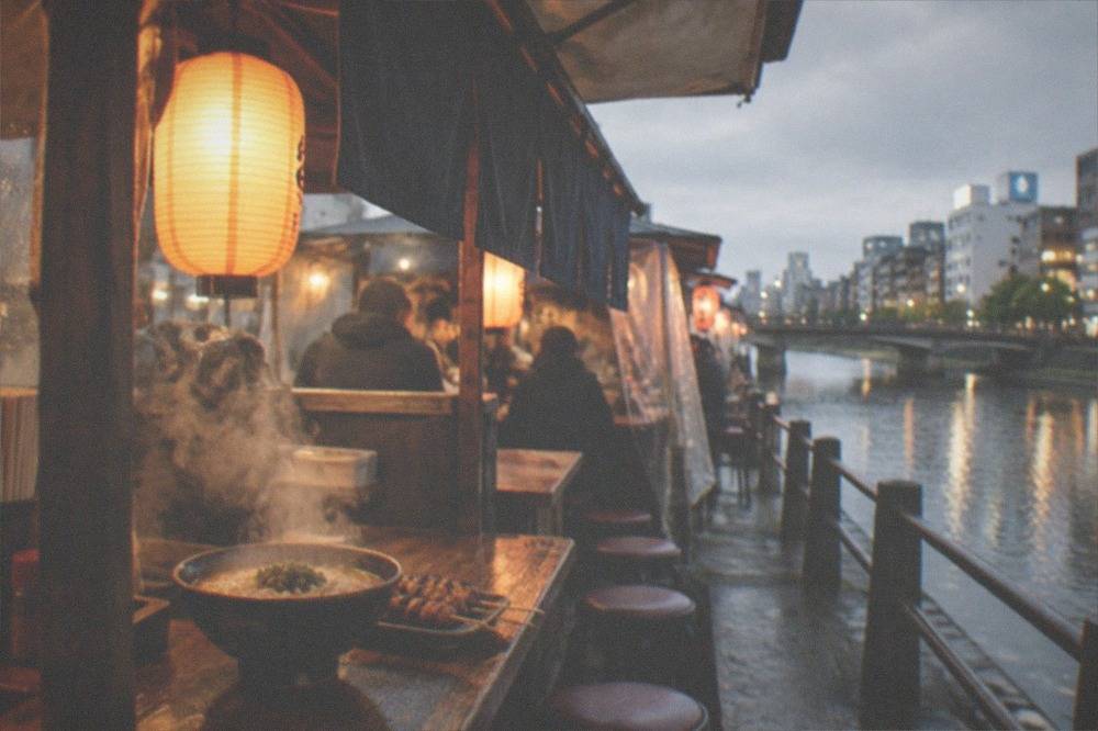 Bowl of steaming noodle soup and grilled skewers set on a wooden counter under warm lantern light