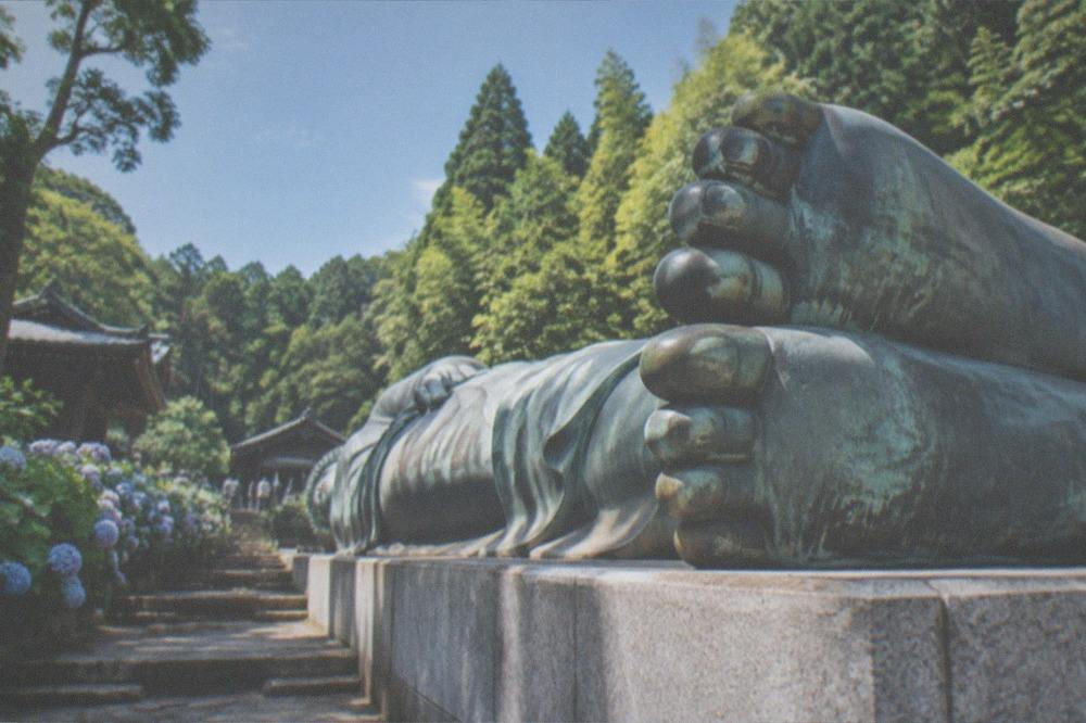 The bronze feet of a giant reclining Buddha statue seen from ground level