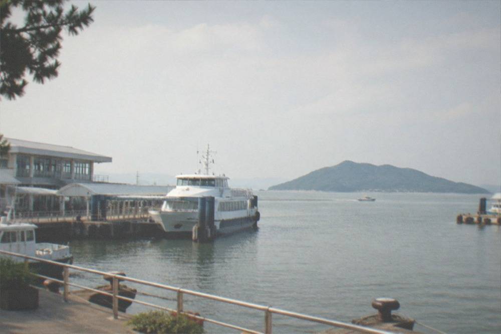 A small ferry terminal building beside a calm bay with an island in the distance