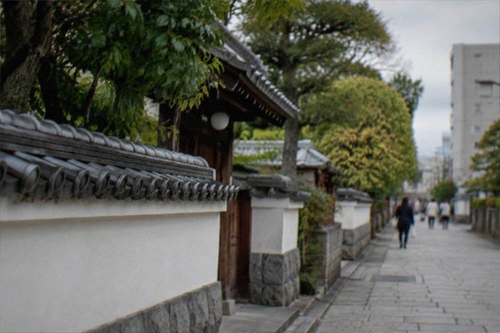 Stone-paved lane with temple walls and trees in the Hakata old town district