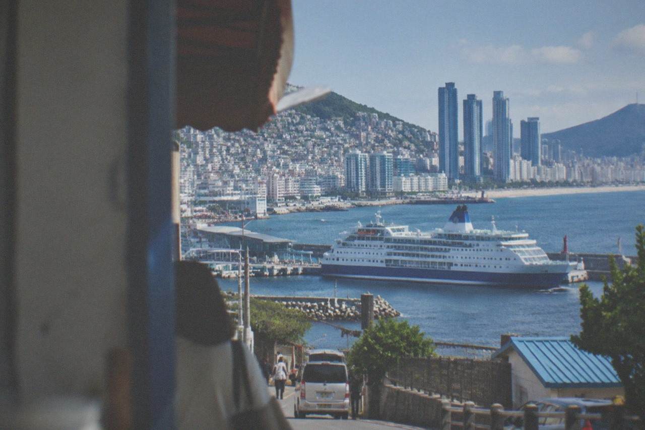 A large passenger ferry moored at a port terminal in Fukuoka with the city skyline behind it