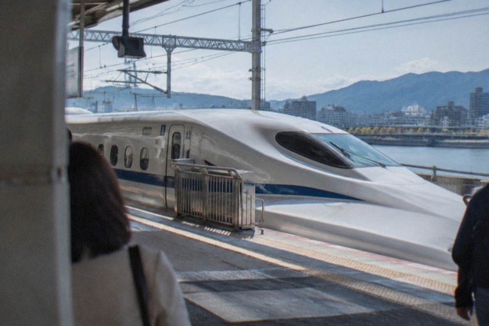 A sleek bullet train stationary at a platform with overhead departure signs