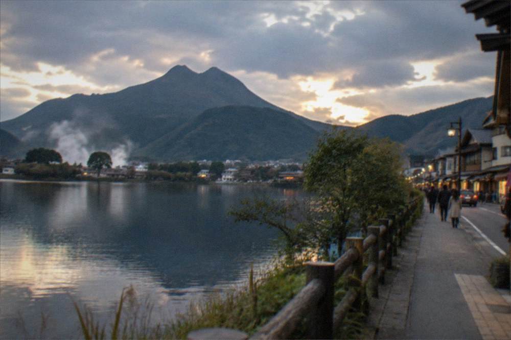 A lake at dusk with soft light on the water and dark hills behind a small town