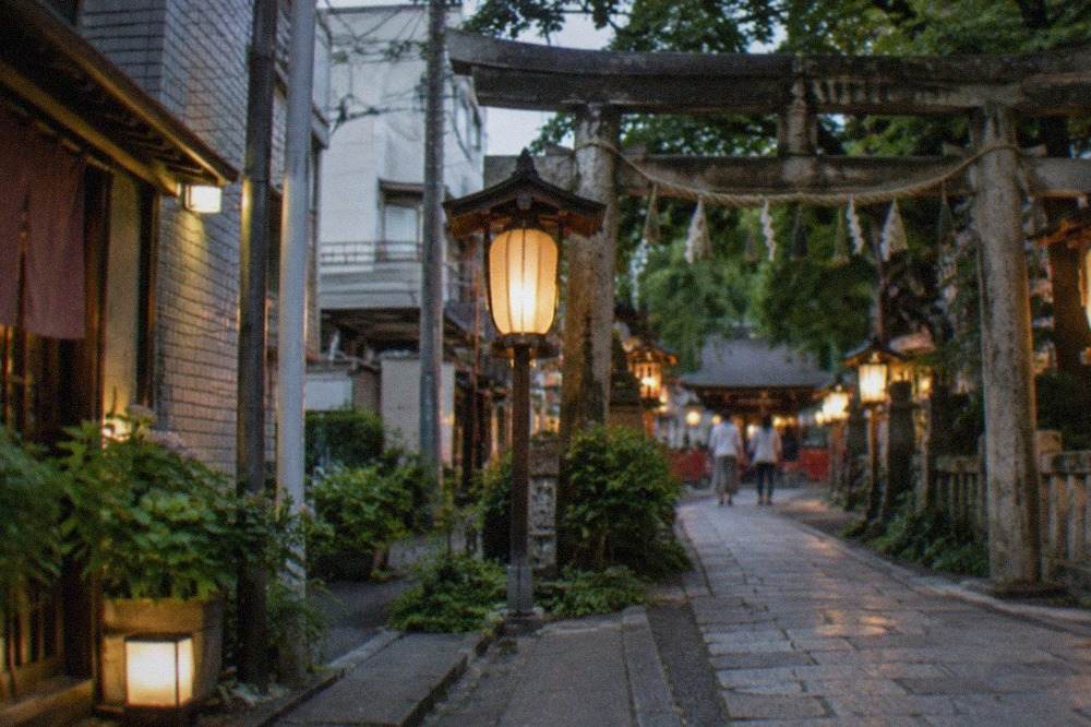 Lantern-lit shrine gate and stone path in Hakata at dusk
