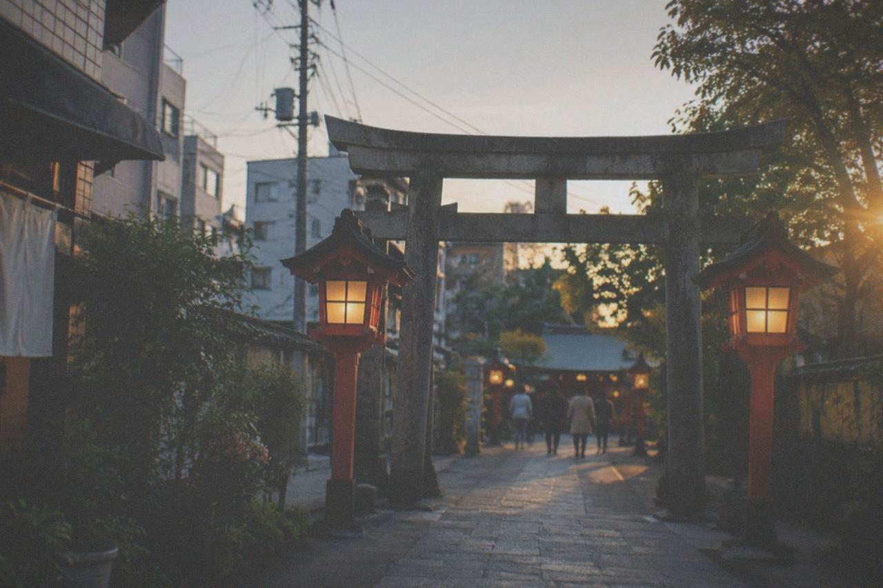 Lantern-lit shrine gate and stone path in Hakata at dusk