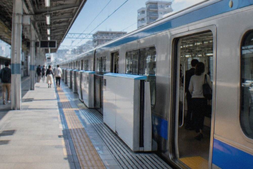A subway platform at Fukuoka Airport station with a train waiting at the doors