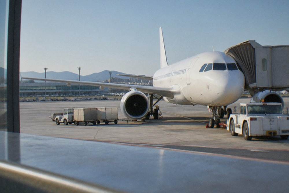 A plane parked at a terminal gate at Fukuoka Airport under a clear sky