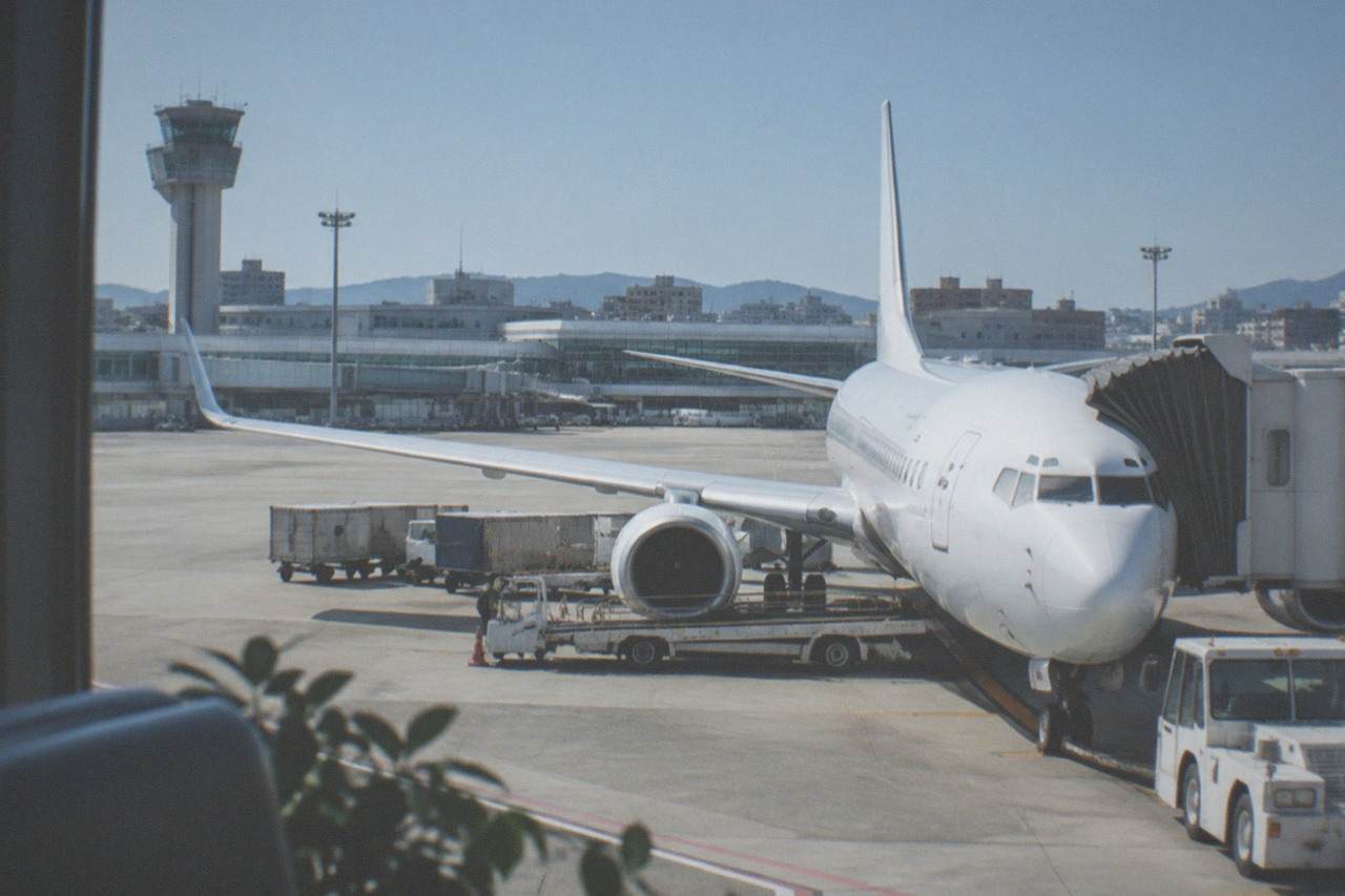 A plane parked at a terminal gate at Fukuoka Airport under a clear sky