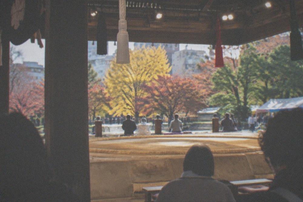 A sumo arena hall with a clay dohyo ring under bright lights before a tournament session