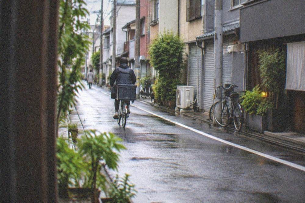 A quiet morning street with closed bar shutters and a delivery bicycle passing