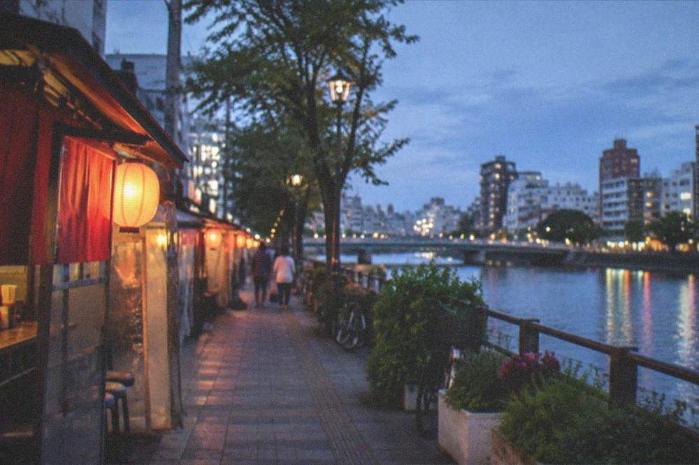Evening food stalls lit by lanterns along a riverside walkway
