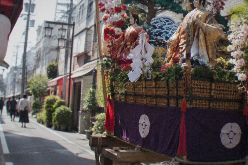 Ornate decorated festival float with dolls and banners standing on a street in Hakata