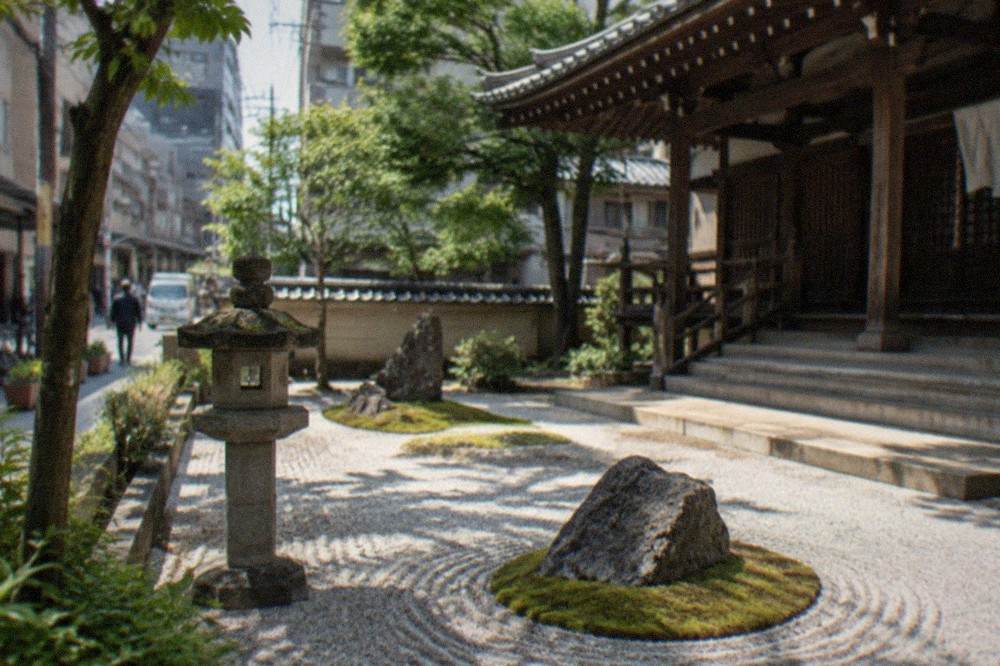 A raked gravel Zen garden with moss patches and stone lanterns beside a wooden temple hall