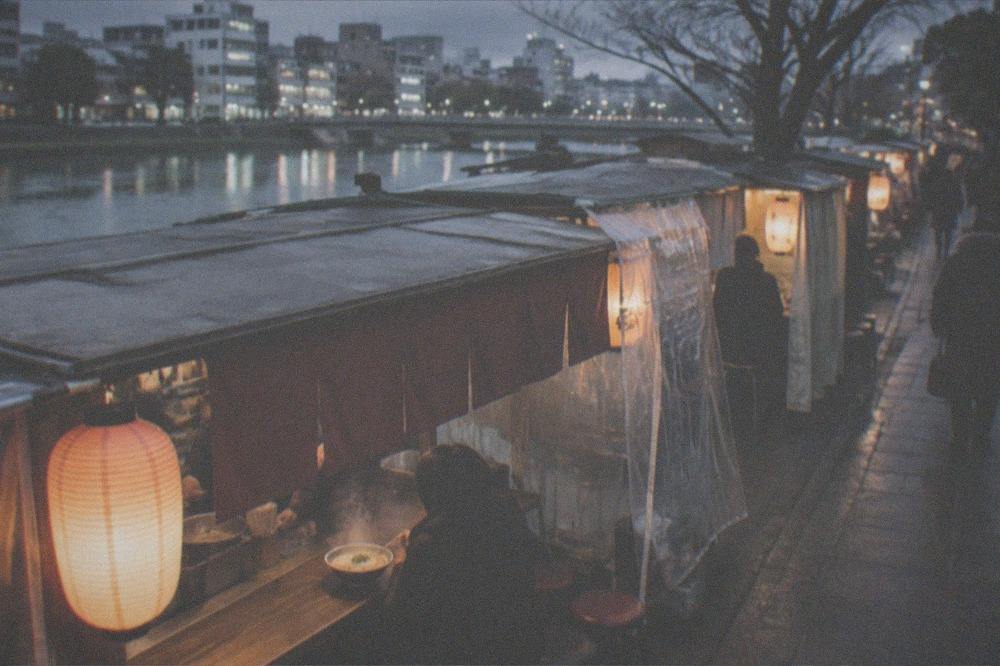 Steam rising from a bowl of tonkotsu ramen on a yatai food stall counter at night in winter