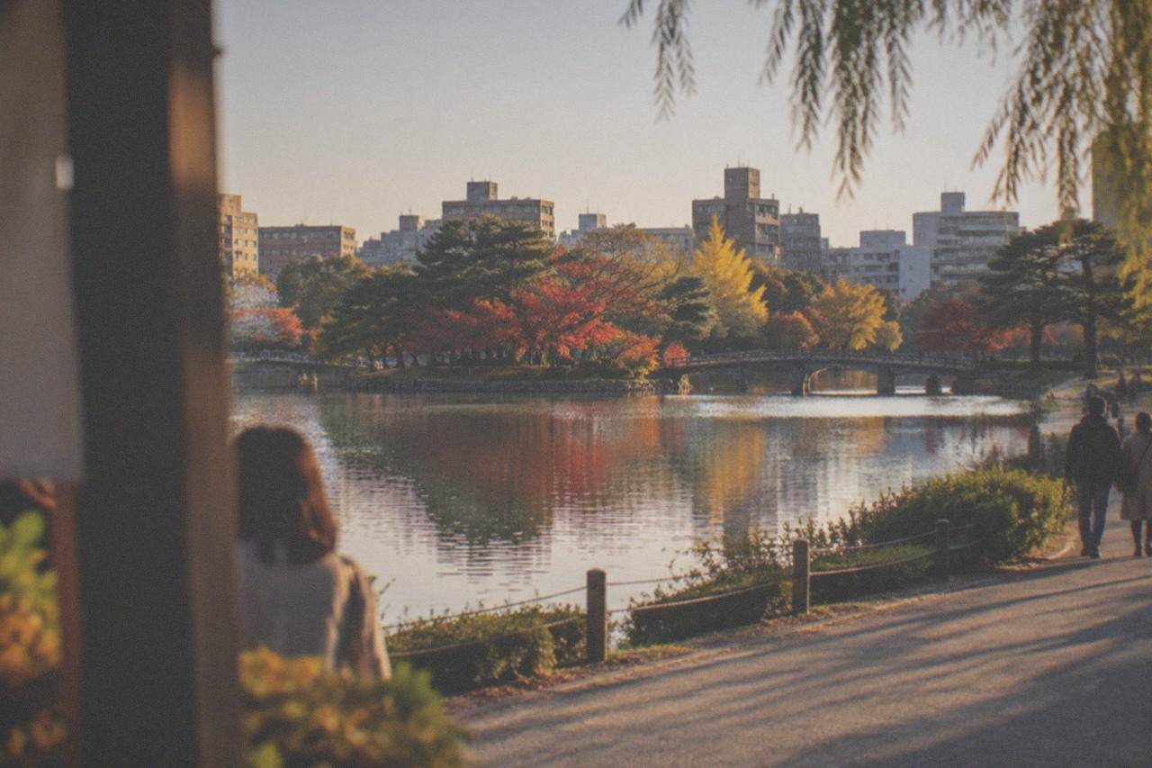 Autumn trees reflected in the water of Ohori Park with the city skyline beyond