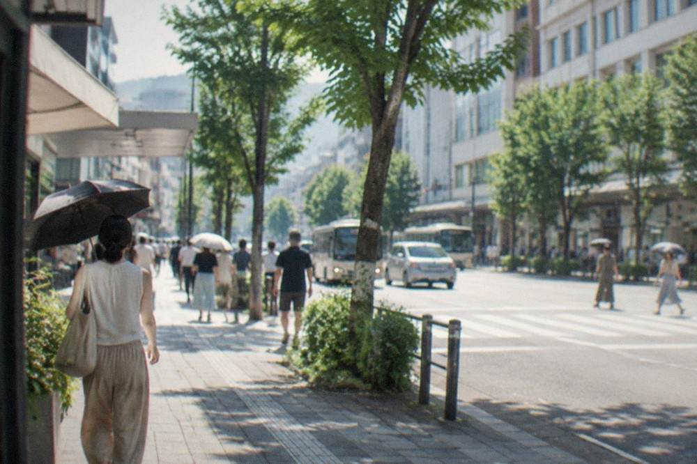 Sunlit street in Tenjin with heat haze over the pavement and shaded shop awnings