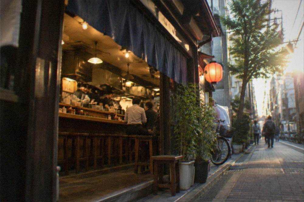 A busy izakaya interior with a long counter and staff working behind it