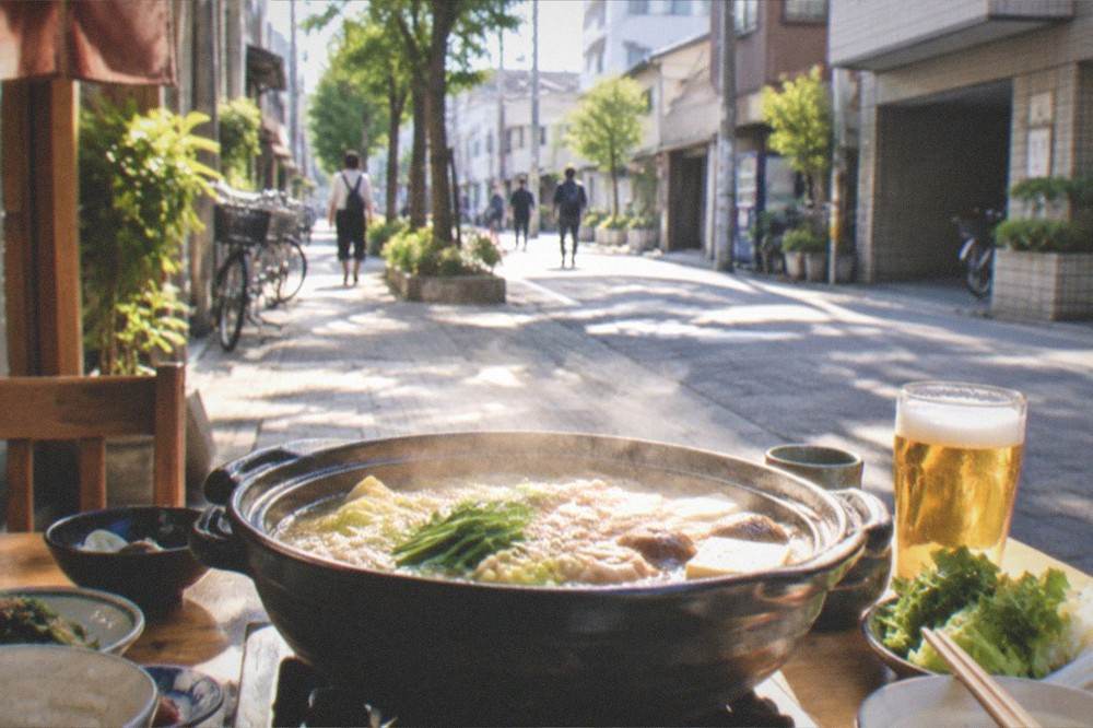 A bubbling hot pot on a table surrounded by small dishes and drinks