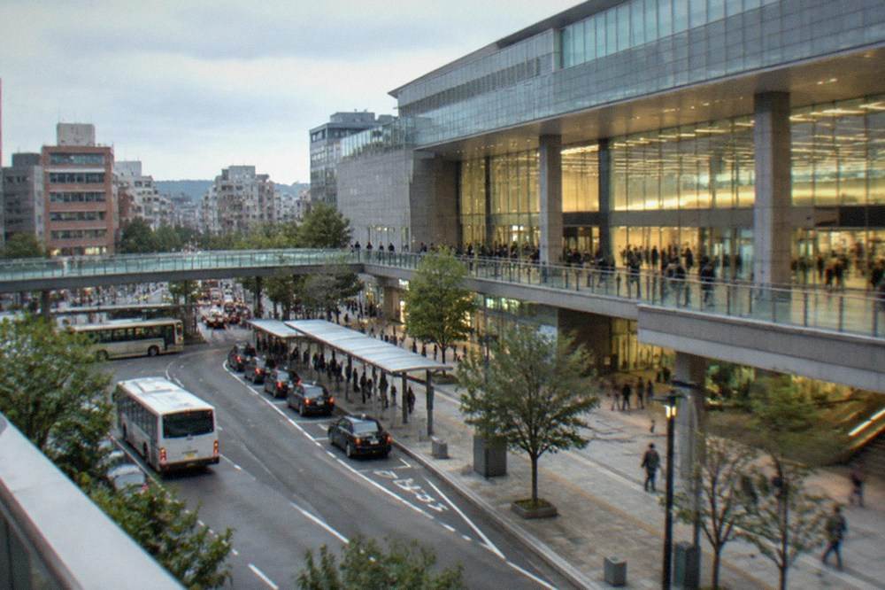 A busy train station concourse with illuminated departure boards and wide gates