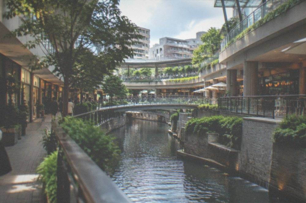 Modern shopping complex interior with a waterway running between terraced retail levels