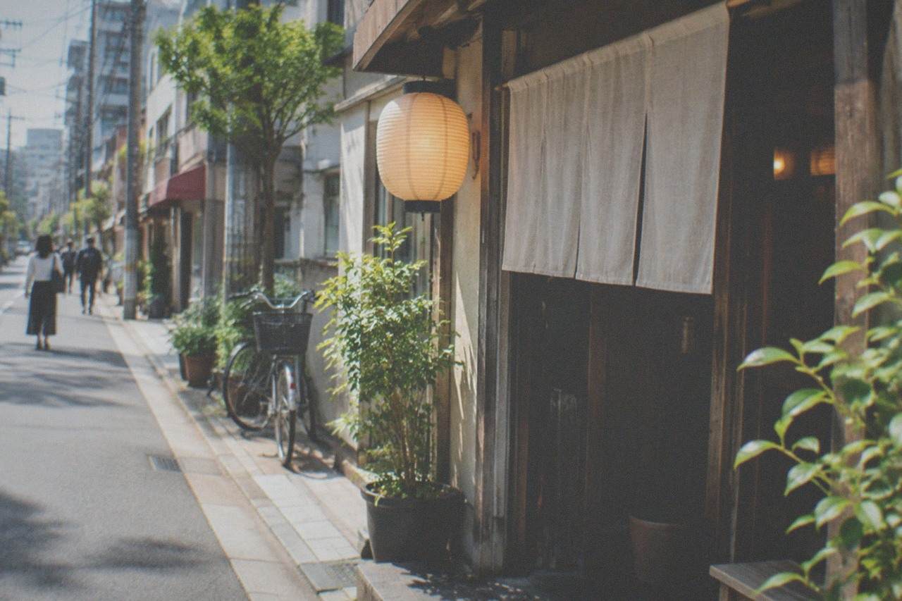 A quiet lantern lit alley in Fukuoka at dusk with small restaurant entrances along the wall