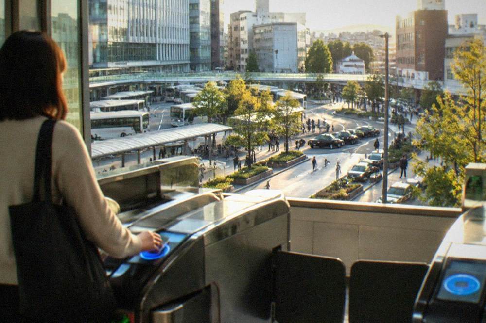 A subway station ticket gate with a commuter tapping a smart card on the reader