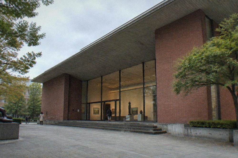 Art museum gallery hall with sculptures on plinths and paintings along the wall