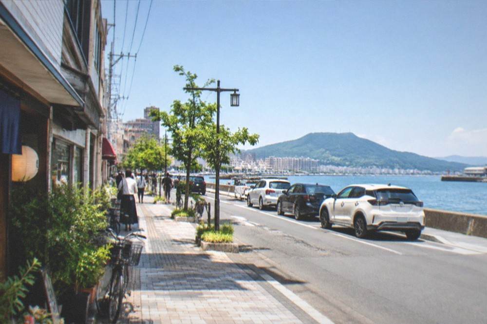 A coastal road with parked cars looking out over a calm bay